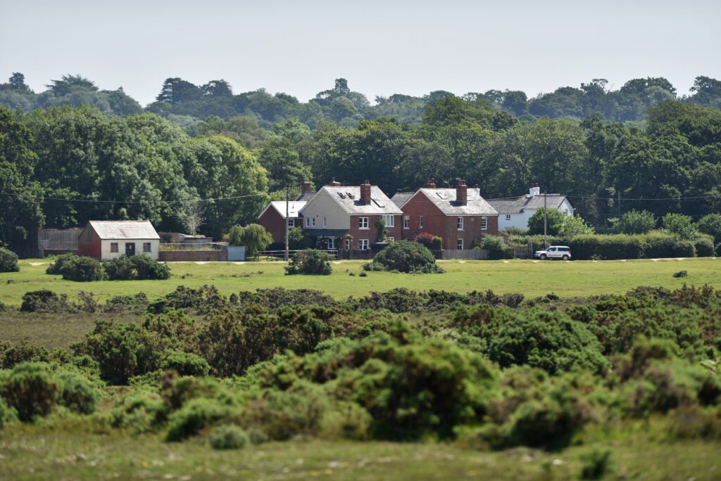 a group of redbrick houses with grassland and trees around
