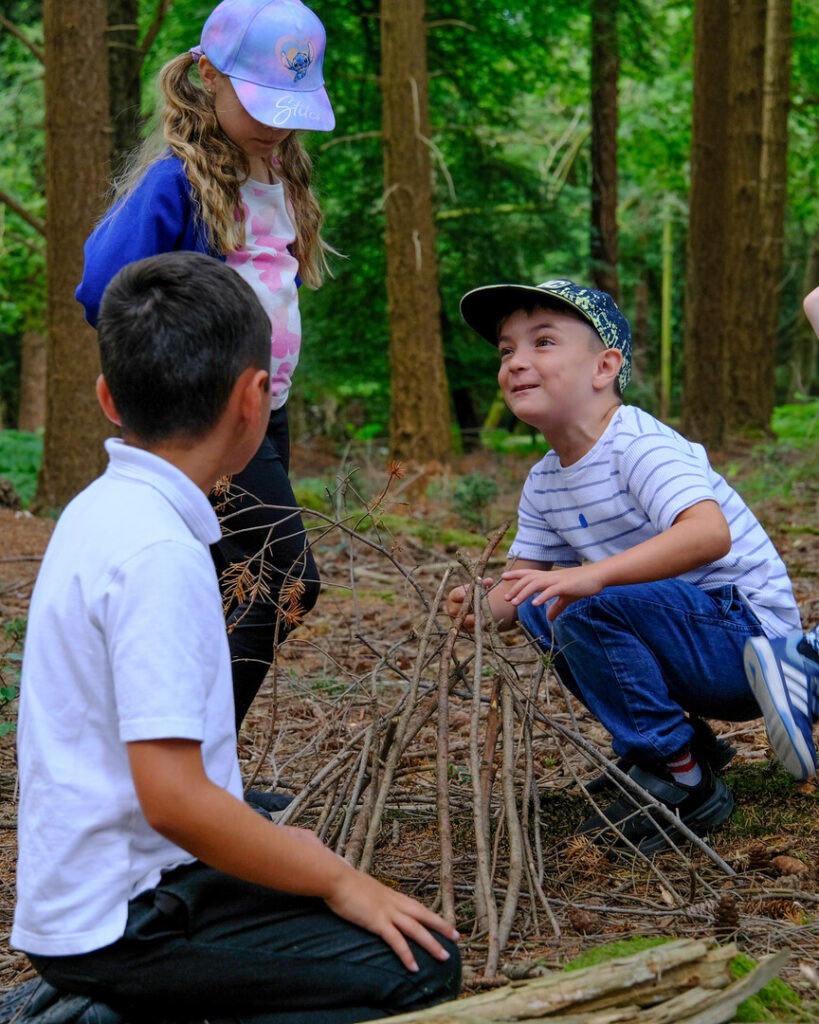 three children building a fire out of sticks in a forest