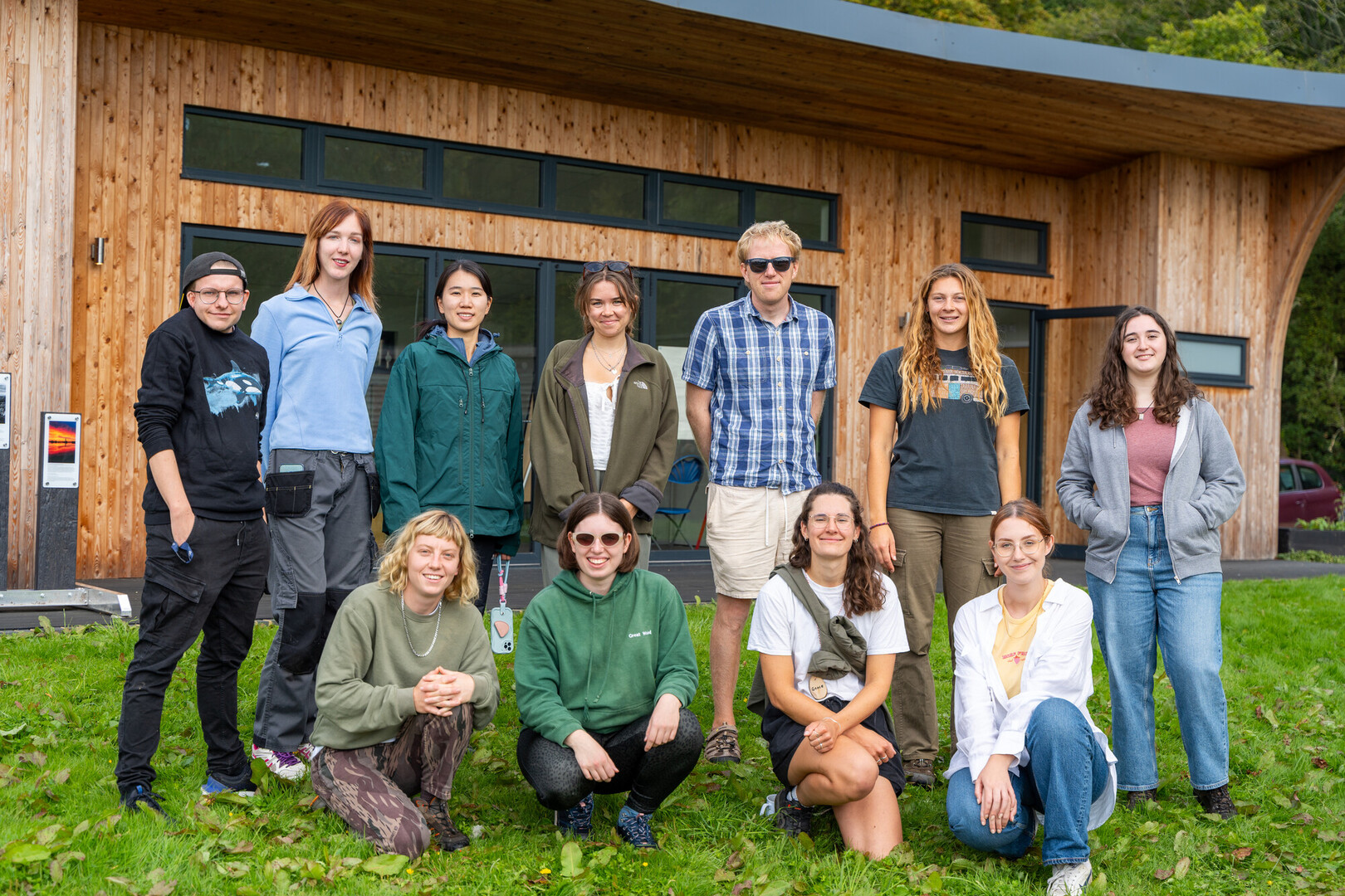 A group of young adults some are standing and some are kneeling in front