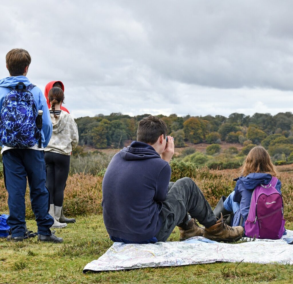 a group of teenagers two sitting and three standing in the countryside