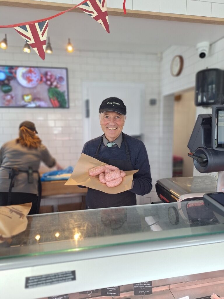 Butcher in shop holding sausages