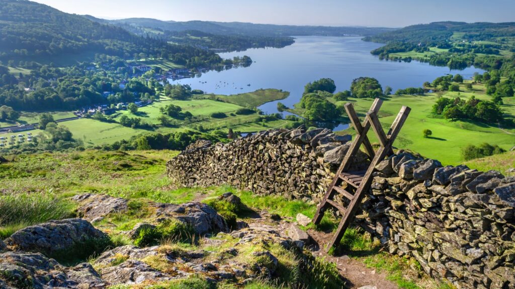 a ladder over a wall with a lake and mountains behind