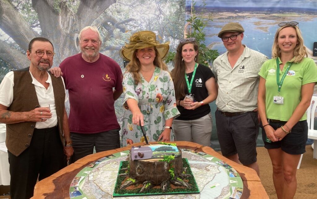 a group of people standing behind a table with a cake