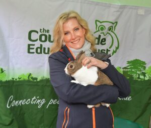 A woman holding a rabbit in front of a sign