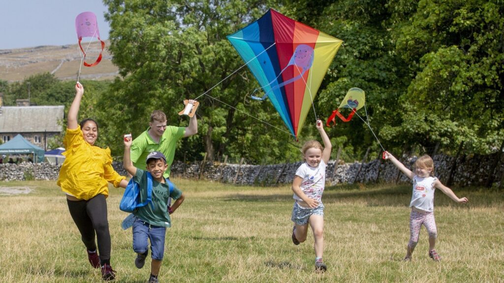 a group of children running in a field with kites