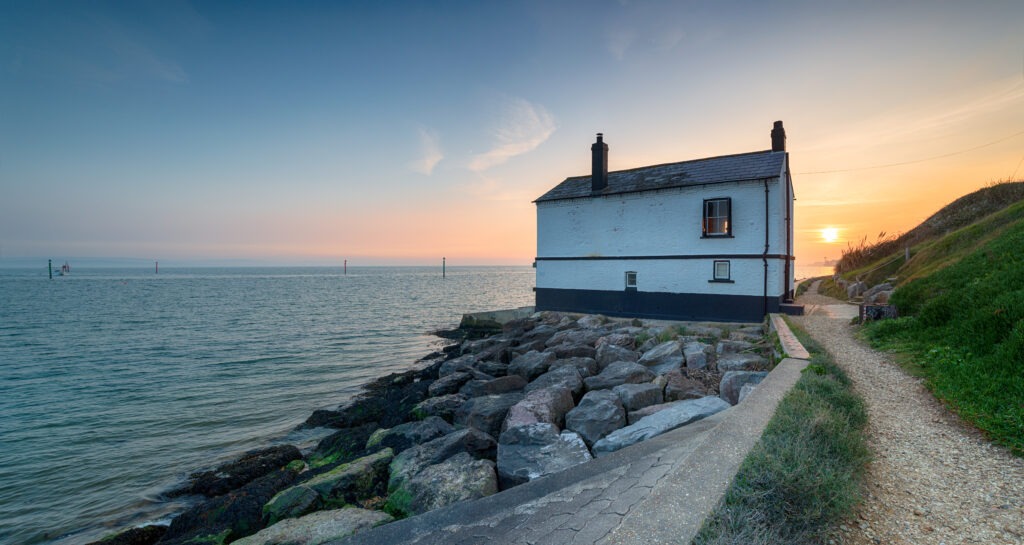 an old coastal building at sunset with the sea behind