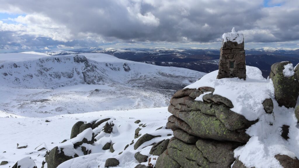 A snowy mountain summit looking on mountains below