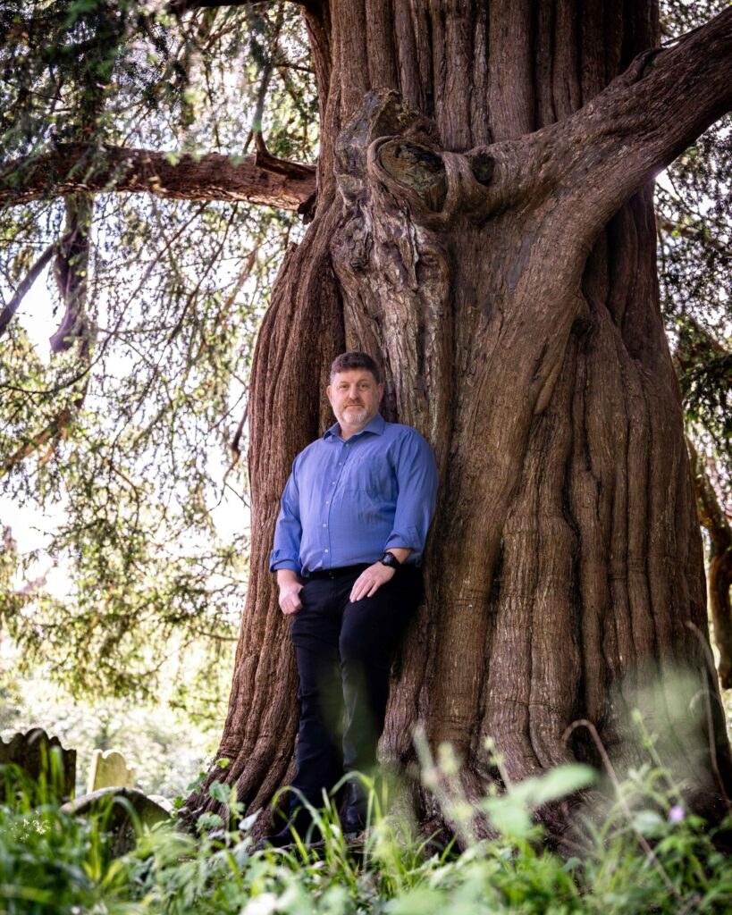 a person in a blue shirt leaning against a tree