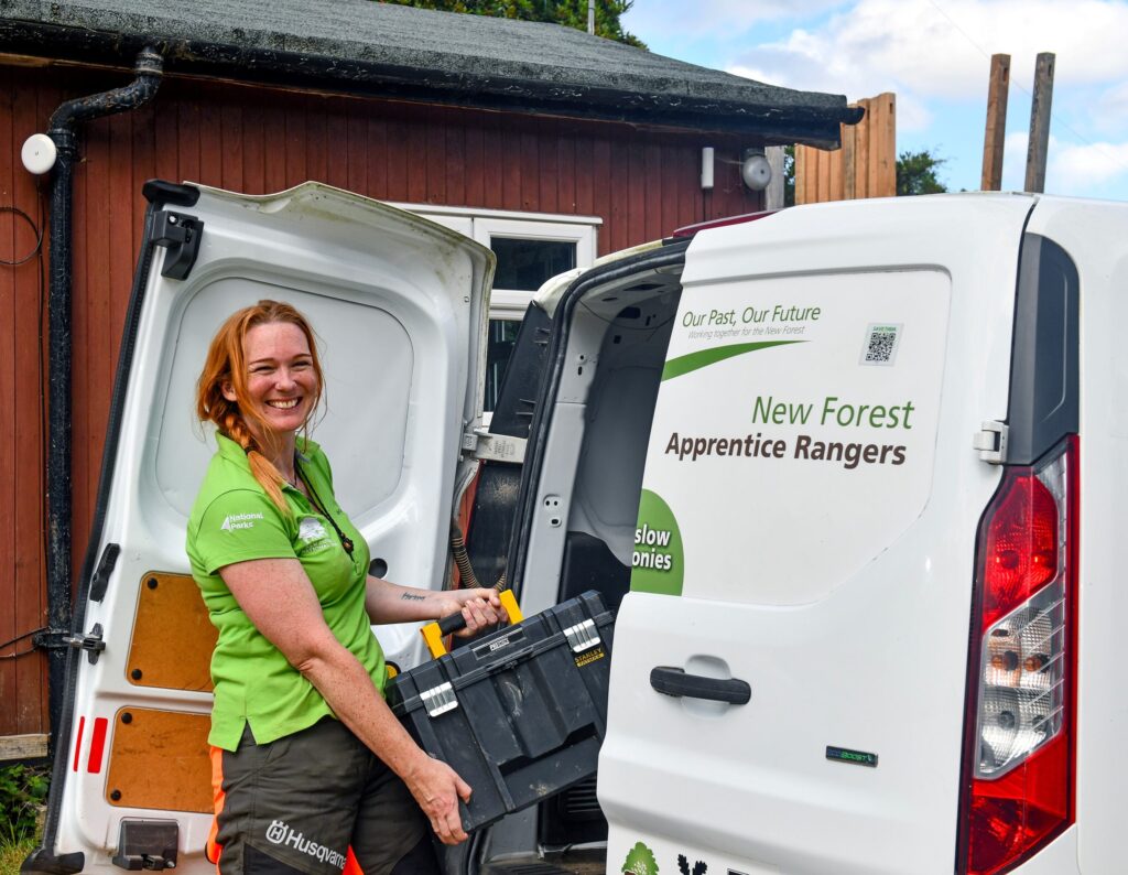 A woman loading a toolbox into a van