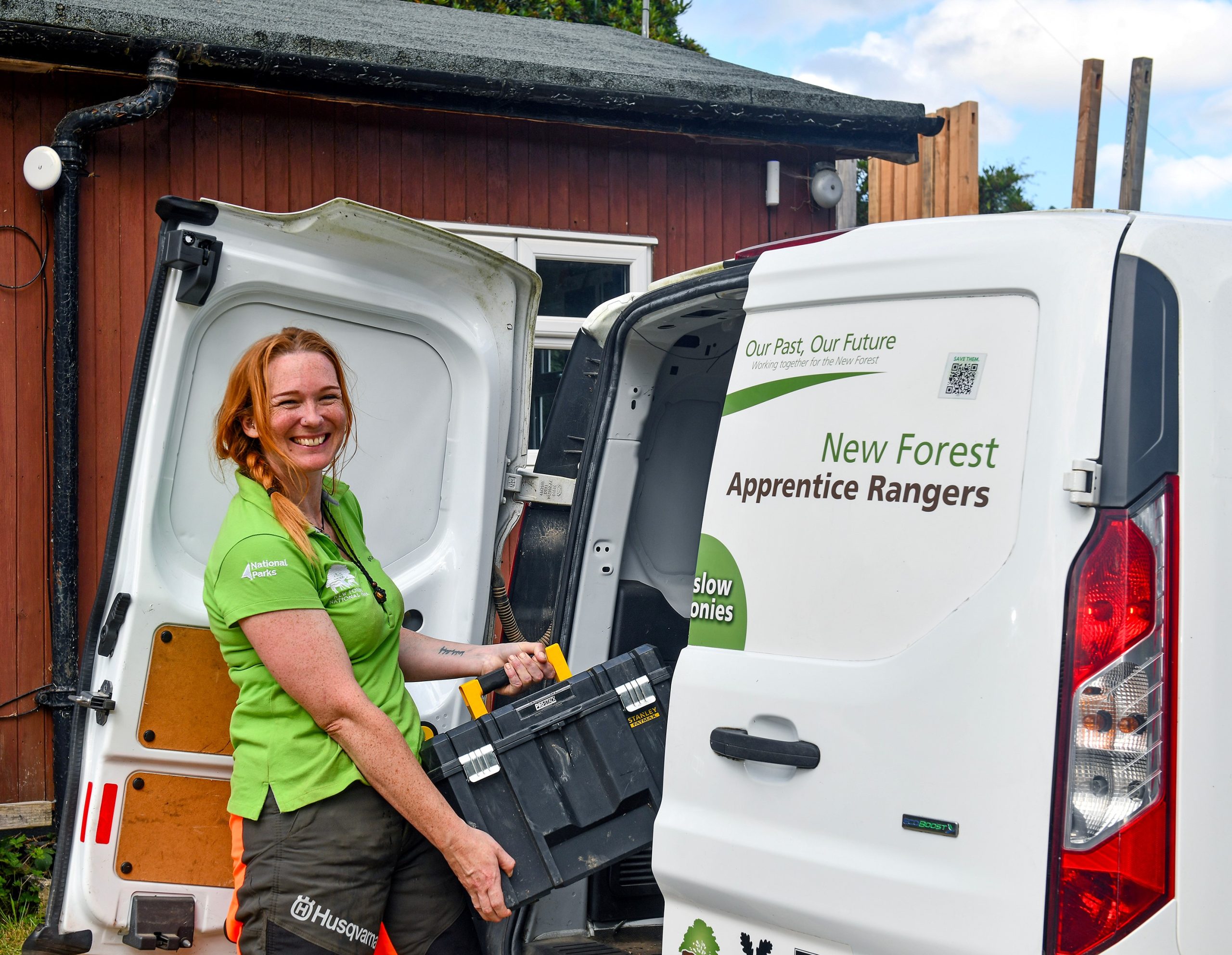 A woman loading a toolbox into a van