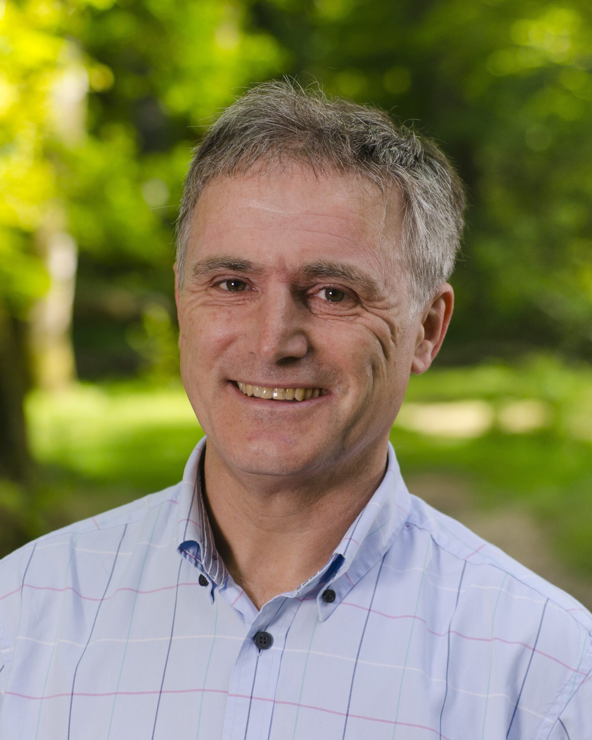 head and shoulders of a person wearing a shirt with trees behind