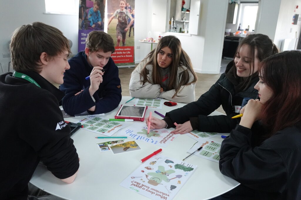 A group of young adults sat at a table with worksheets and pens.