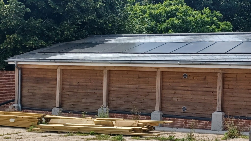 A long wooden-clad building with solar panels