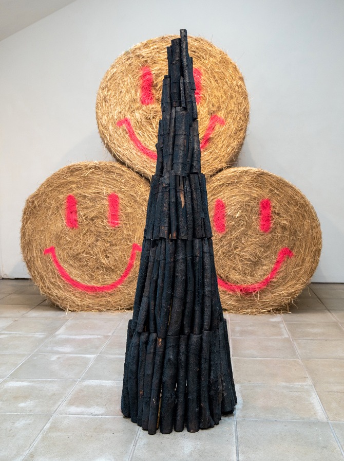 Charcoal and hay sculptures in a gallery