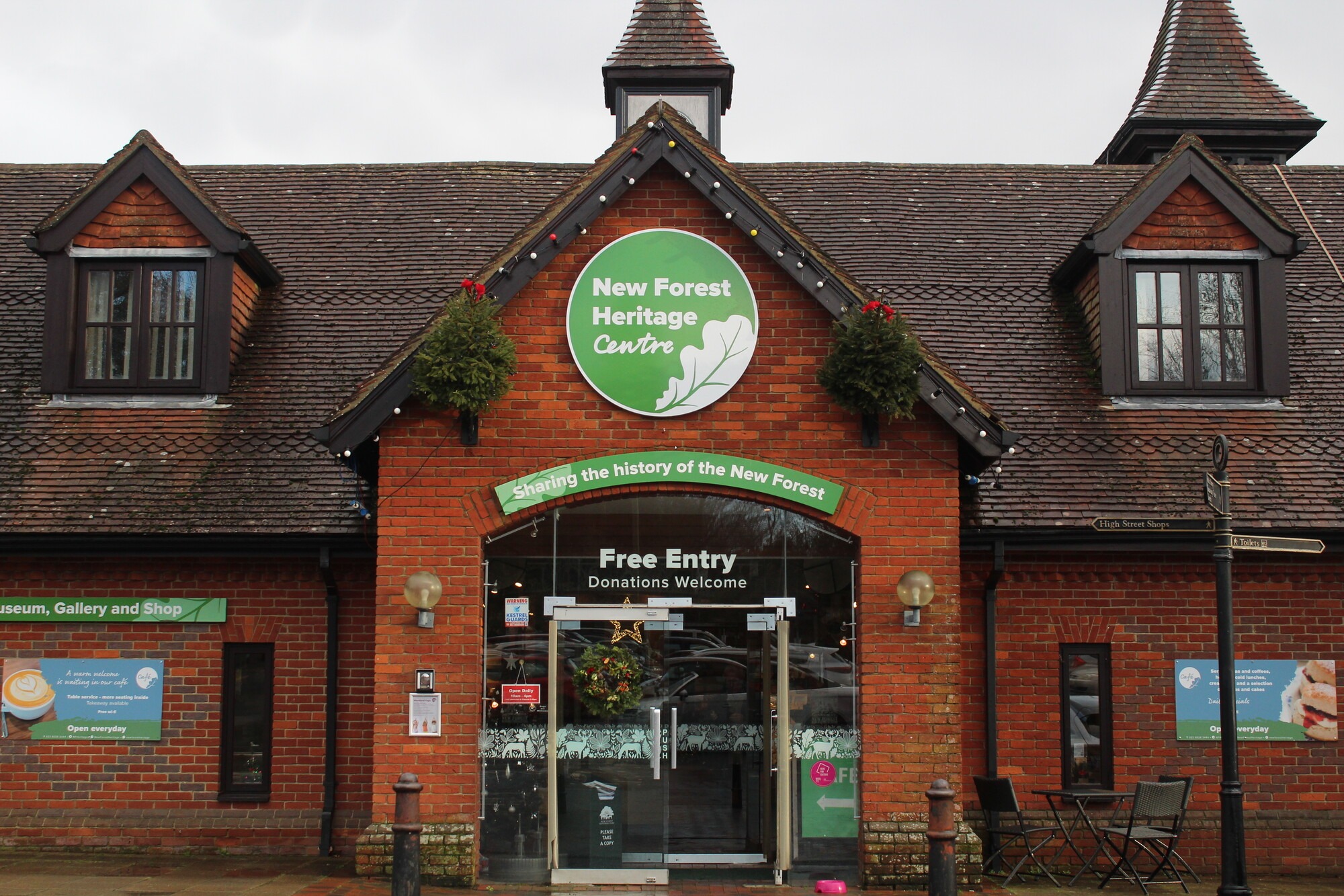 Front entrance of the New Forest Heritage Centre, a brick building with green sign above glass doors reading Free Entry
