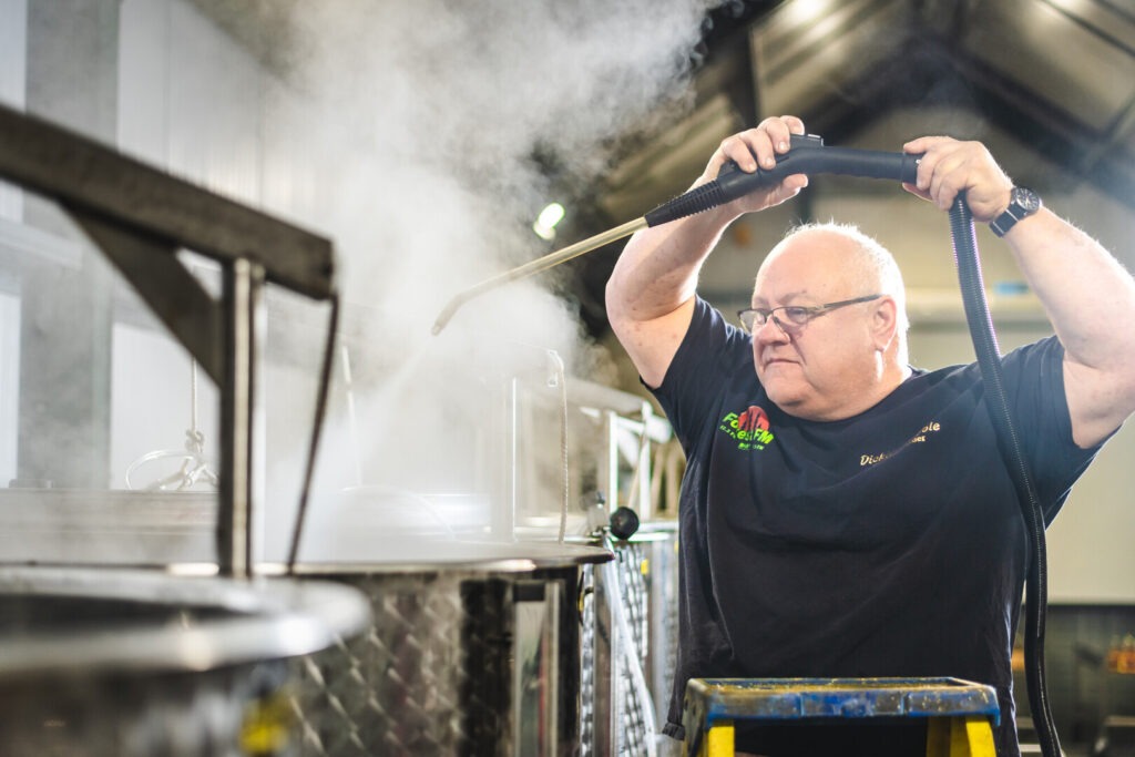 Man in a cider brewery holding up equipment