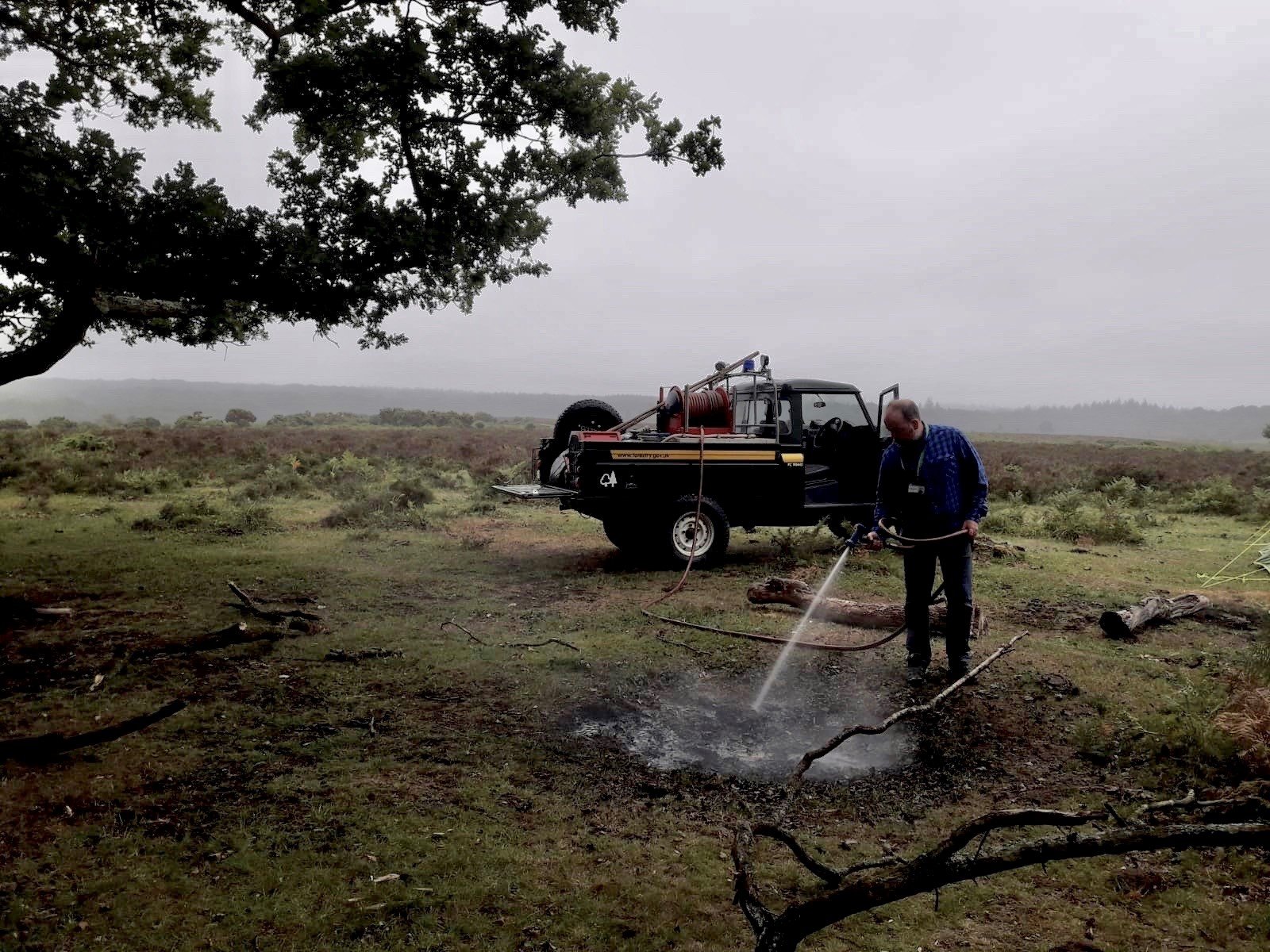 A member of Forestry England puts out a the remains of a bonfire