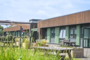 Foundation and Independence Hub at Brockenhurst College, showing timber-clad building with green columns and outdoor seating area