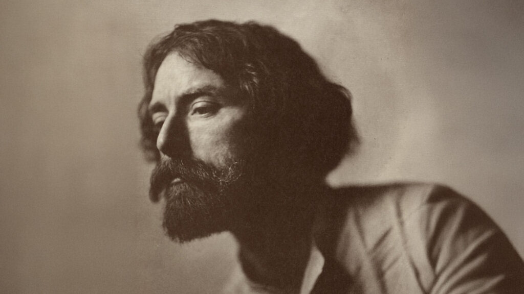 Sepia portrait of a bearded man with wavy hair in side profile, looking left against a plain background