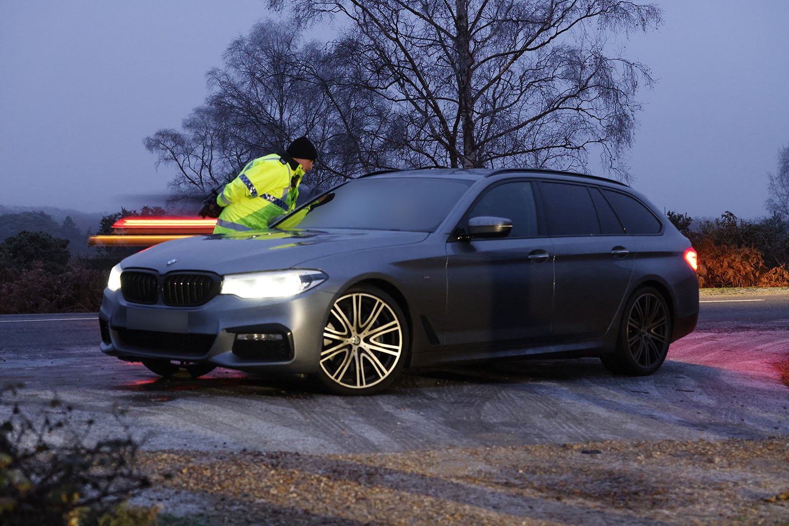 official in hi vis talking to a car driver at night on the frosty roadside