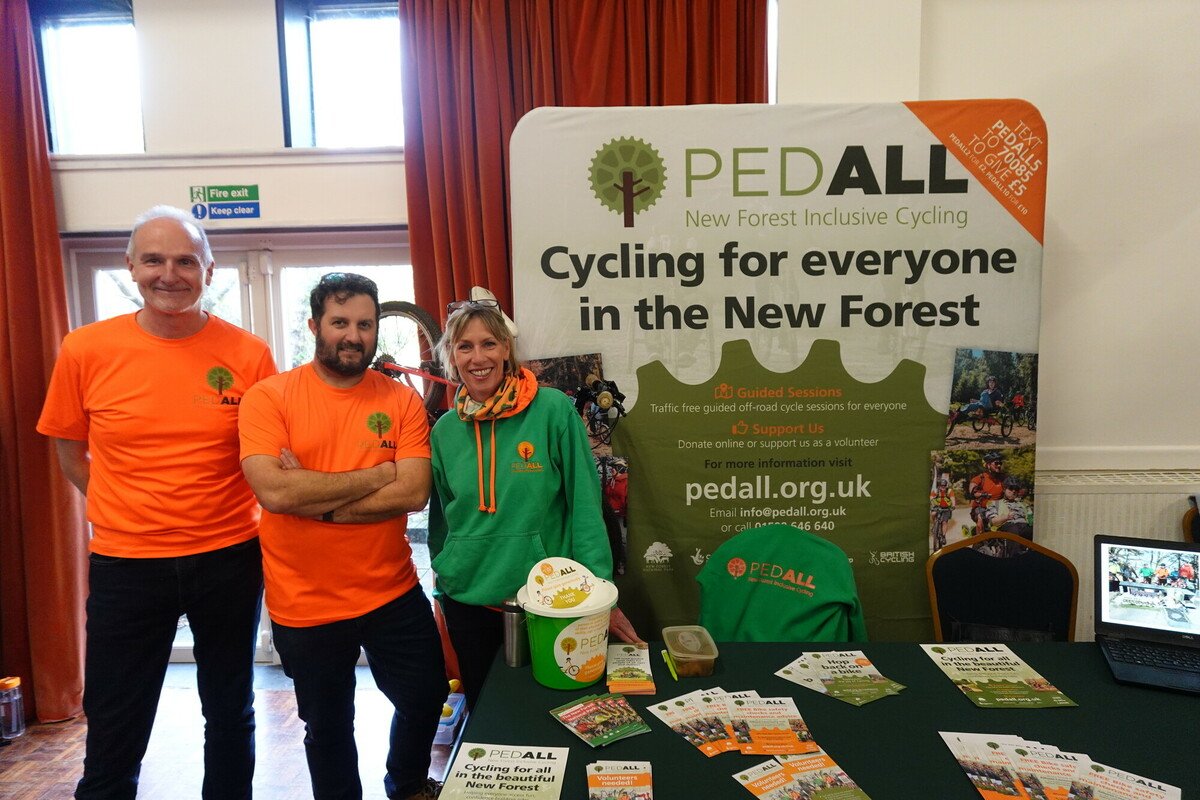 PEDALL staff and a volunteer in front of their information stand in a village hall