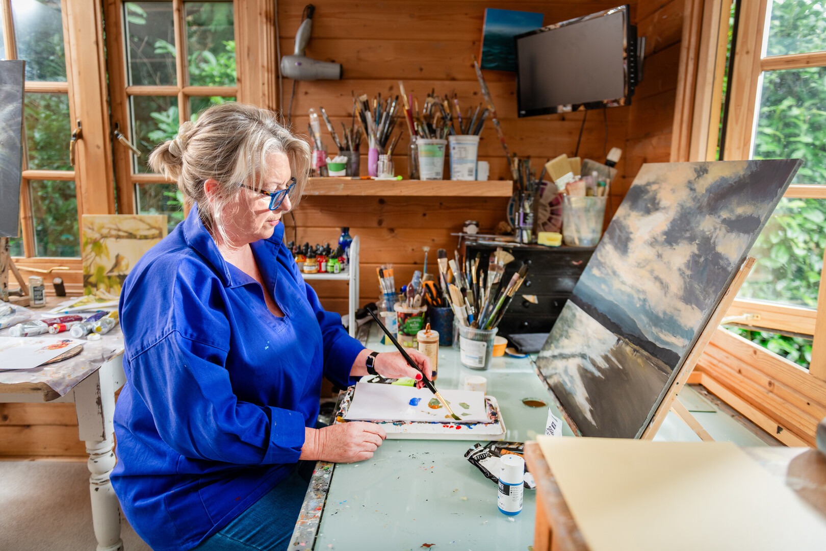 Artist Sandra Binney painting in her art studio. Credit Chris Russel Photography.