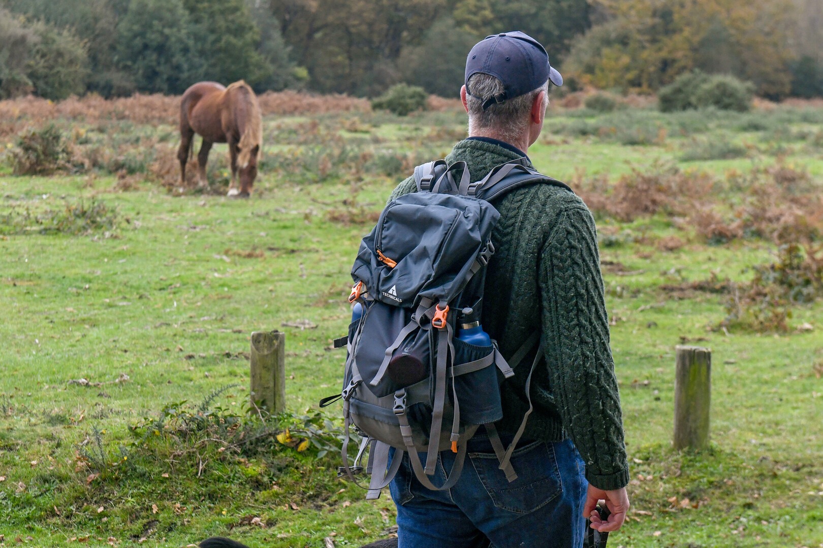 Walker with a bag on stands away from a New Forest pony, keeping his distance.
