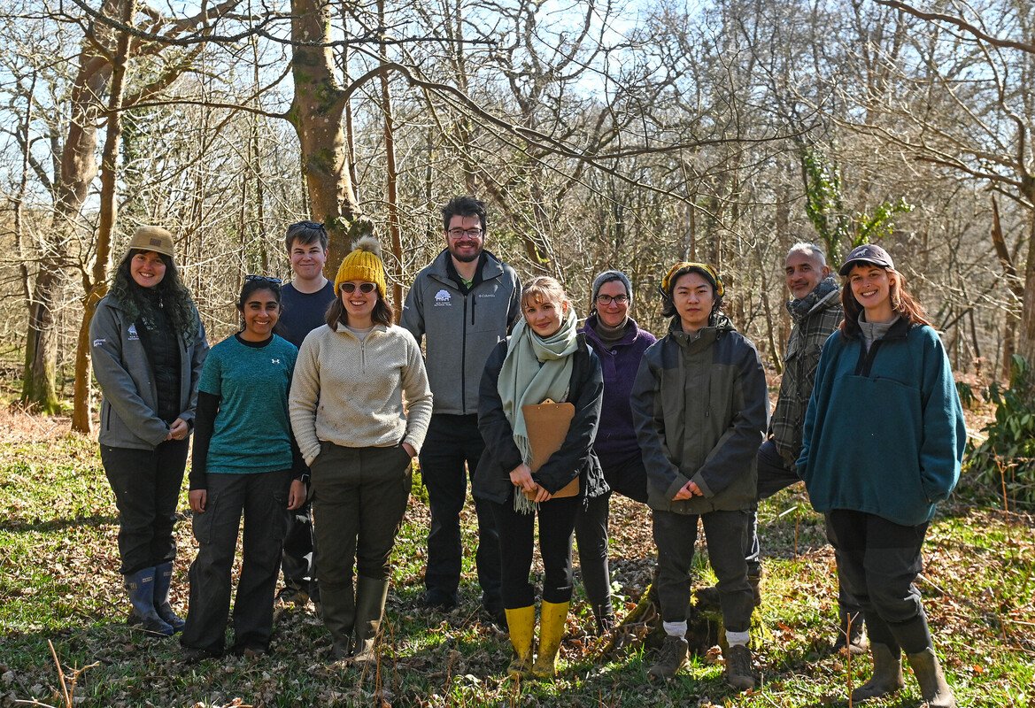 A group of staff and volunteers stood in a wooded area