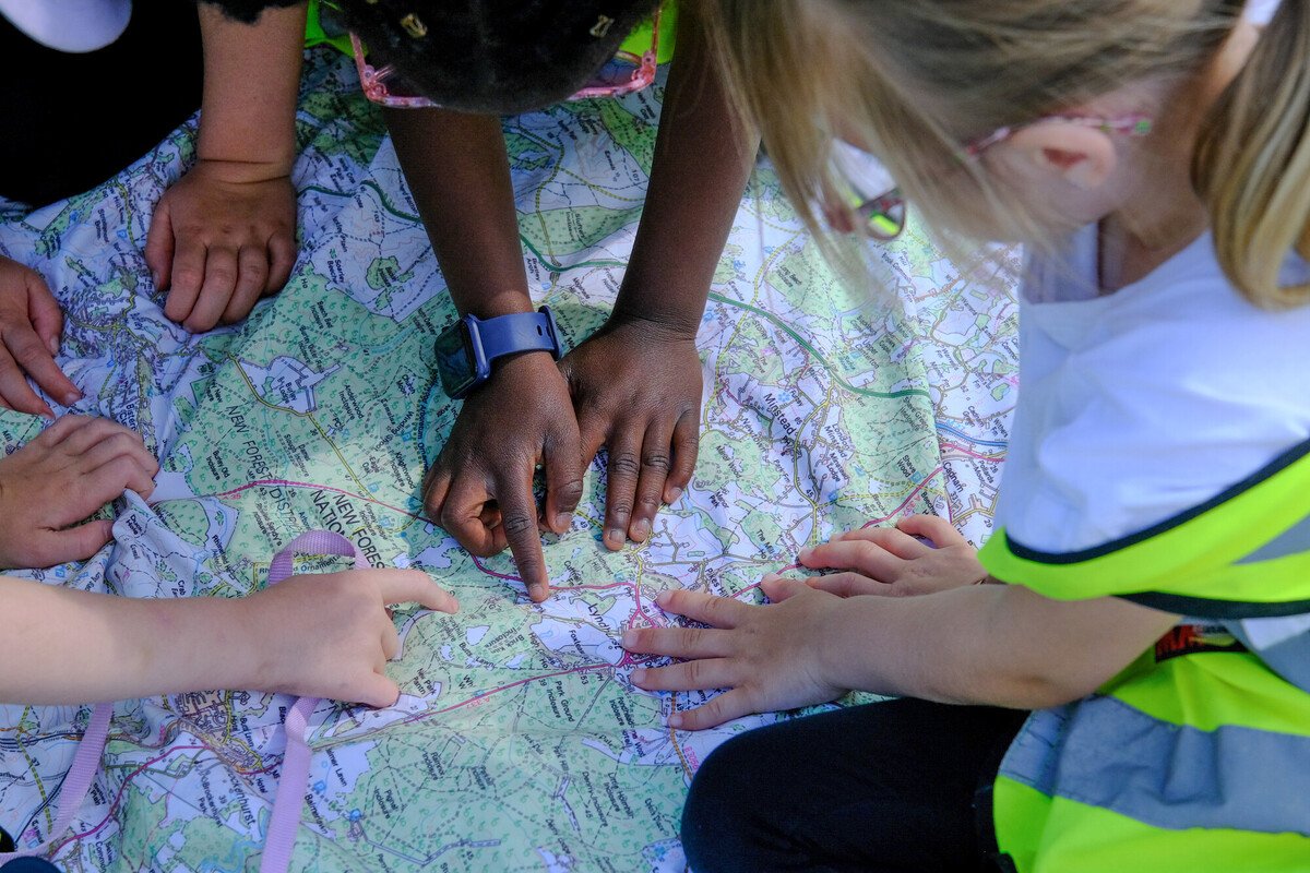 Young people pointing at an area of the New Forest on a large map 