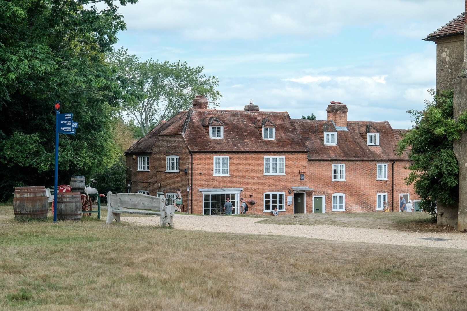 Line of buildings at Buckler's Hard with blue sky, grass and a path.