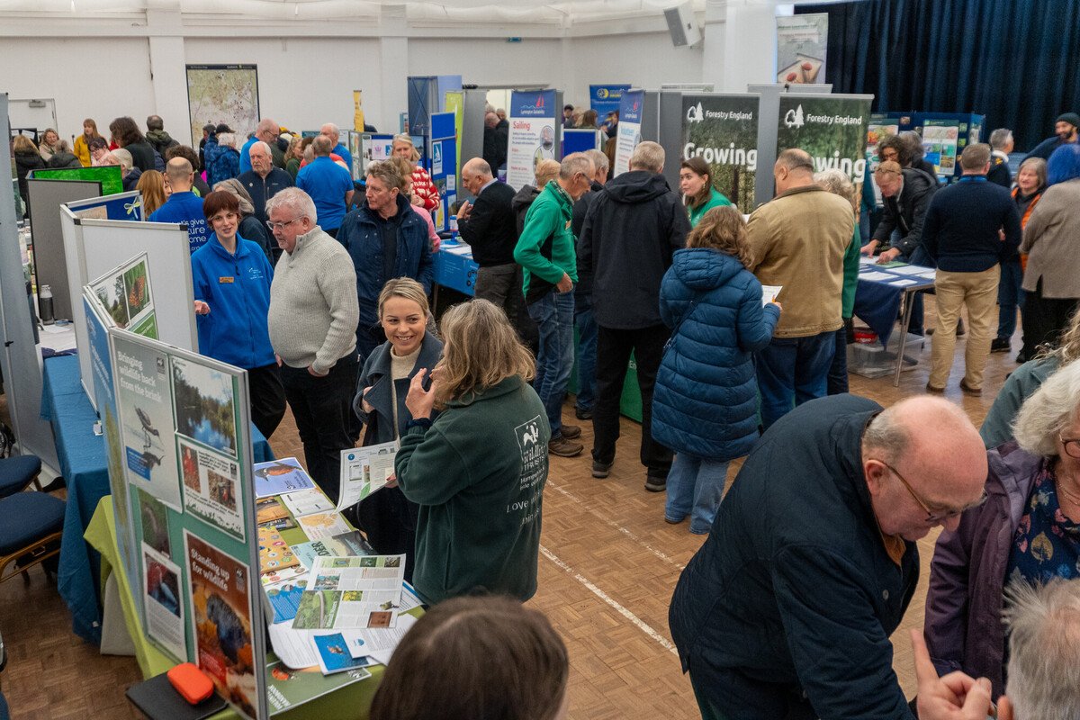 A village hall full of information boards and lots of people in discussion.
