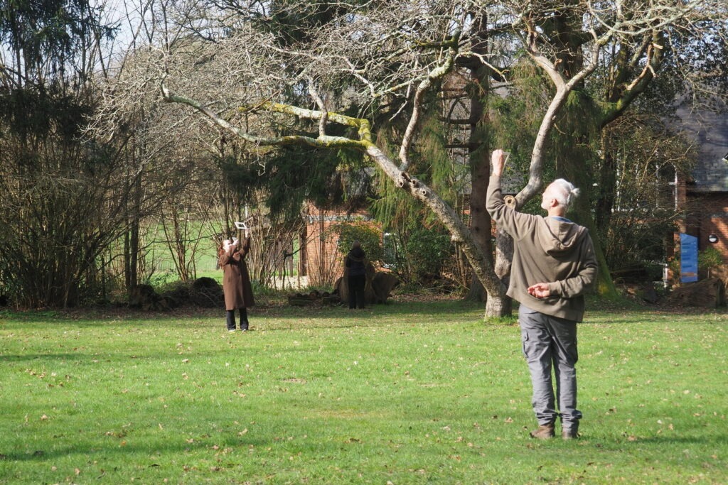 Two Connect and Learn attendees stand in a field with trees as part of a nature connection session.