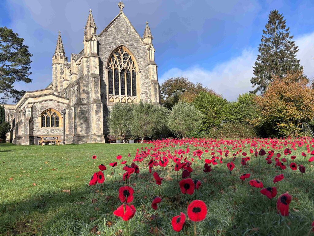 St Saviour's Church in Brockenhurst with a field of red remembrance poppies on the lawn in front under a blue sky